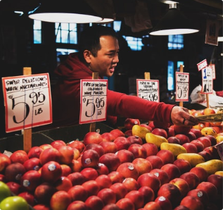 A picture of a man reaching over a fruit stand